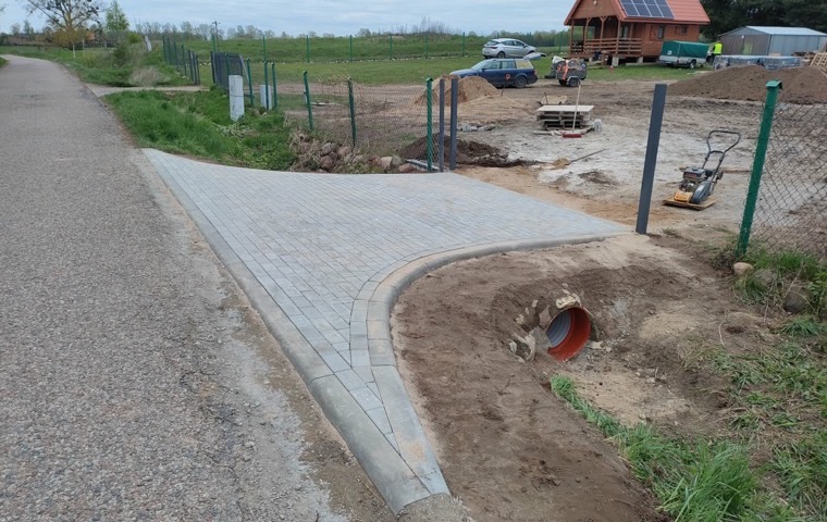 Gotowy zjazd z drogi na działkę wyłożony kostką, z krawężnikami i przepustem