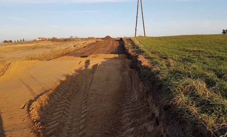 Długi wykop liniowy pod przyłącze biegnący przez pole